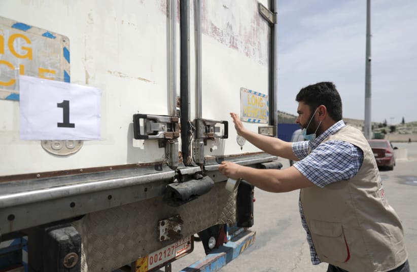 A healthcare worker stands near the truck that carries vaccines against the coronavirus disease (COVID-19) at Bab al-Hawa crossing at the Syrian-Turkish border, in Idlib governorate, Syria April 21, 2021.  (photo credit: REUTERS/KHALIL ASHAWI)
