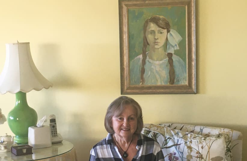 EVA BERGSTEIN sits under a painting of her mother Hena, drawn from a photograph (photo credit: COURTESY EVA BERGSTEIN)