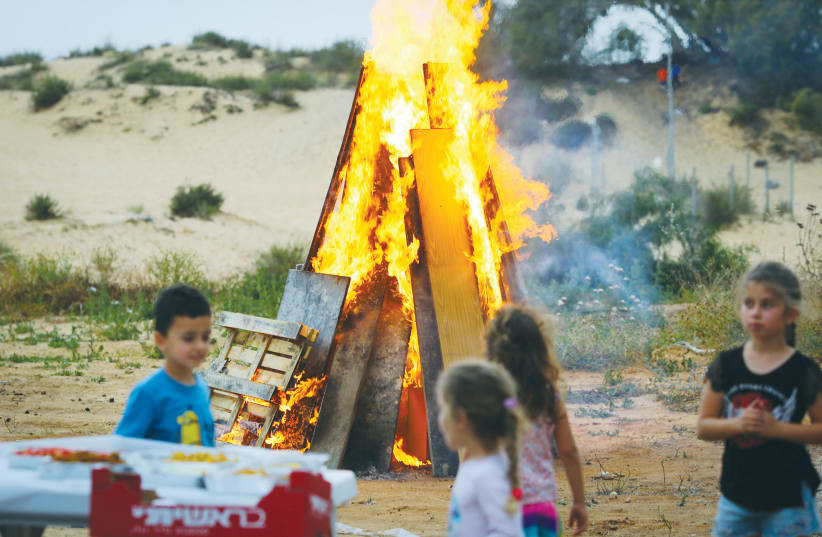 CHILDREN GATHER around a bonfire to celebrate Lag Ba’omer in Ashdod in 2018. (photo credit: FLASH90)