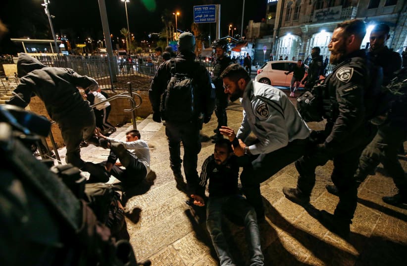 Police Officers clash with Palestians at Damascus Gate in Jerusalem on April 21, 2021. Clashes erupted after Israeli police put barriers that prevented people from sitting on the steps in the plaza outside the gate.  (photo credit: JAMAL AWAD/FLASH90)
