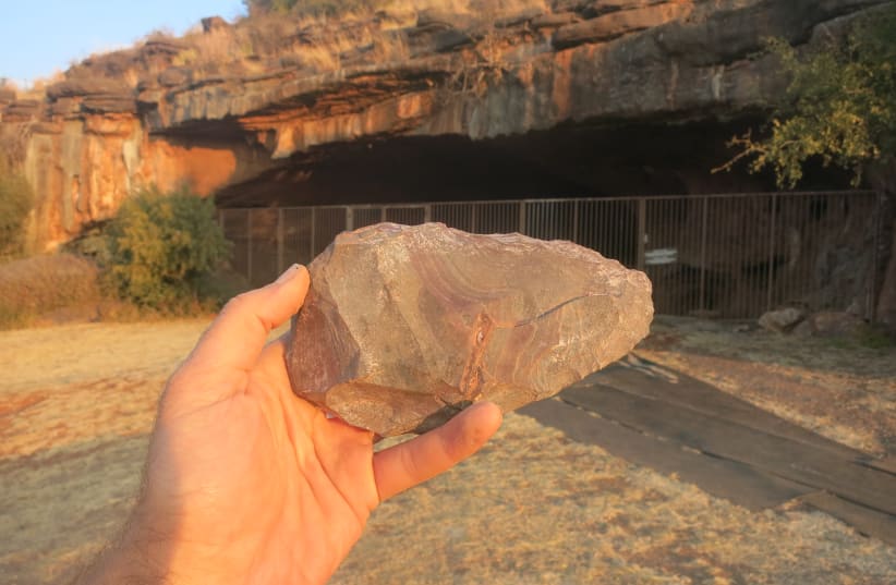 A handaxe from the Achelean layers at Wonderwerk, South Africa. In the background is the cave entrance.  (photo credit: COURTESY OF MICHAEL CHAZAN AND THE WONDERWERK EXCAVATION TEAM)