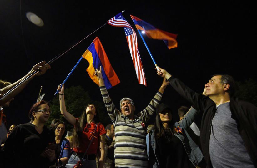 People wave Armenian and US flags in front of the US Embassy in the Armenian capital Yerevan after President Joe Biden recognized the 1915 killings of Armenians by Ottoman forces as genocide, April 24, 2021.  (photo credit: KAREN MINASYAN/AFP VIA GETTY IMAGES)