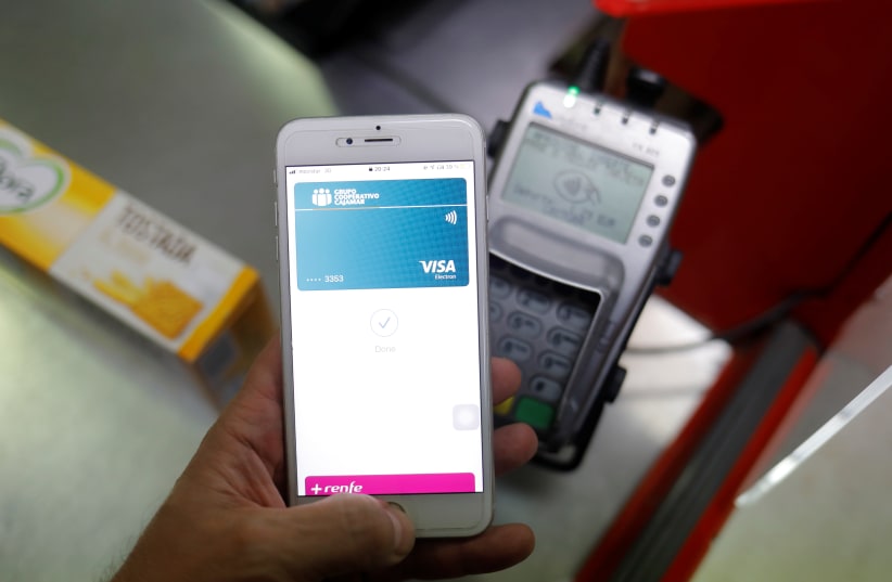 A shopper uses the mobile payment service Apple Pay at a supermarket, amid the coronavirus disease (COVID-19) outbreak, in Ronda, southern Spain October 9, 2020 (photo credit: REUTERS/JON NAZCA)