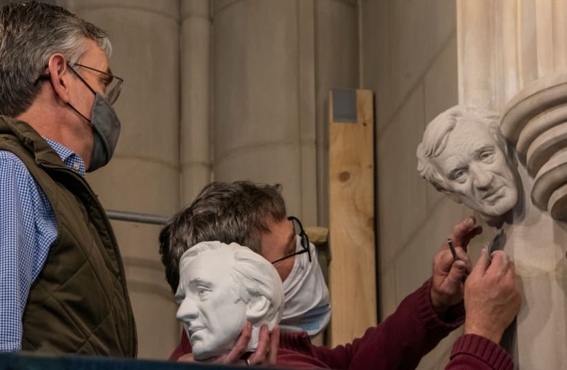 In this undated photo, sculptor Chas Fagan, left, holds a clay model of a bust of Elie Wiesel and watches as stonemason Sean Callahan, right, uses medieval techniques to carve the bust into the walls of the National Cathedral in Washington, DC. (photo credit: NATIONAL CATHEDRAL)