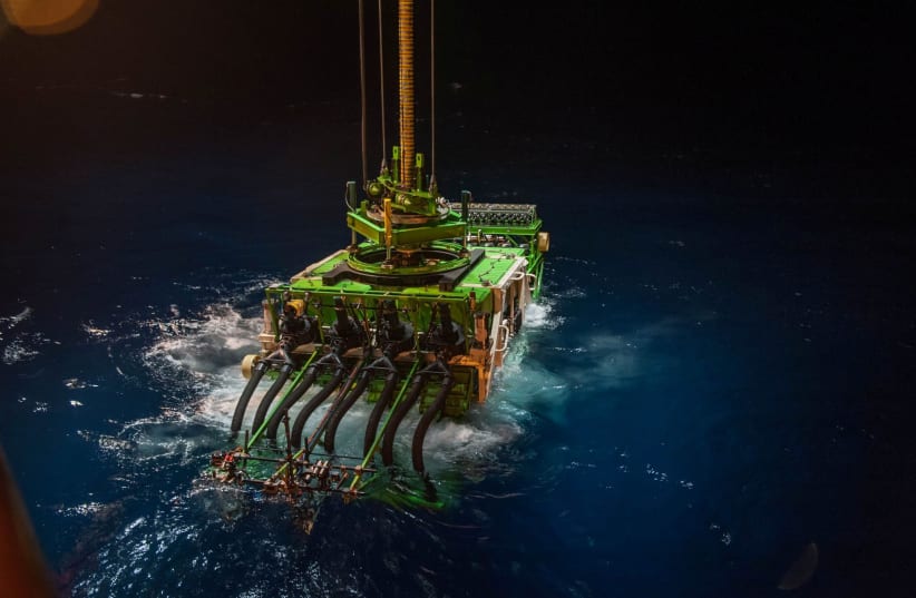 Patania II, a 25-tonne seabed mining robot, is lowered into the Pacific Ocean to begin a descent to the sea floor, in the Clarion Clipperton Zone of the Pacific Ocean, April 2021.  (photo credit: GSR/HANDOUT VIA REUTERS)