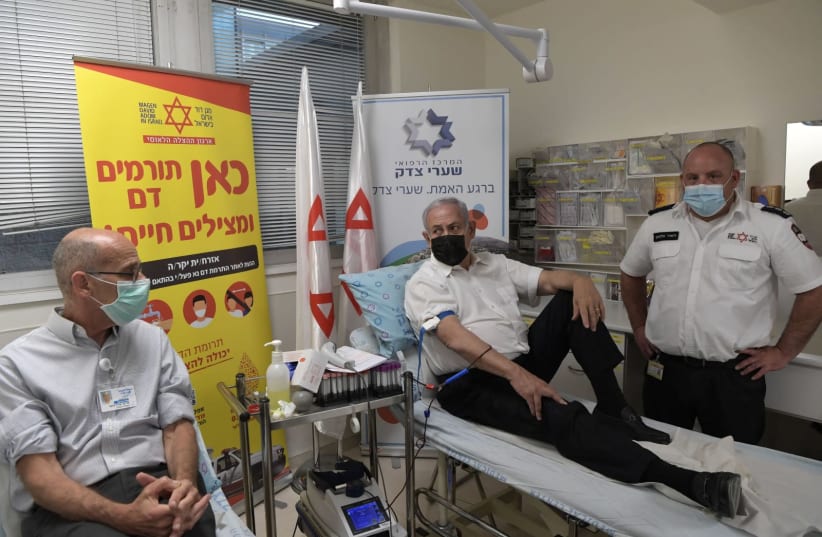Prime Minister Benjamin Netanyahu donates blood at Shaare Zedek Hospital in Jerusalem following the disaster that occurred at Mt. Meron. (photo credit: KOBI GIDEON/GPO)