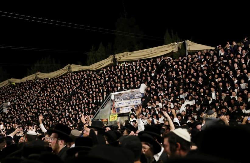Jewish worshippers sing and dance as they stand on tribunes at the Lag B'Omer event in Mount Meron on April 29, 2021  (photo credit: REUTERS/STRINGER)