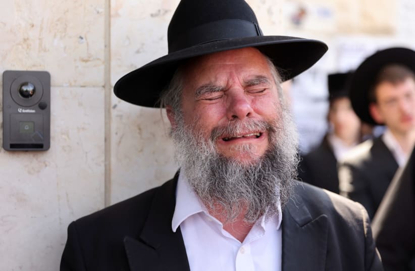Ultra-Orthodox Jewish man reacts as he takes part in a funeral for Rabbi Elazar Goldberg after he died during Lag B'Omer commemorations, in Jerusalem on April 30, 2021 (photo credit: REUTERS/RONEN ZEVULUN)