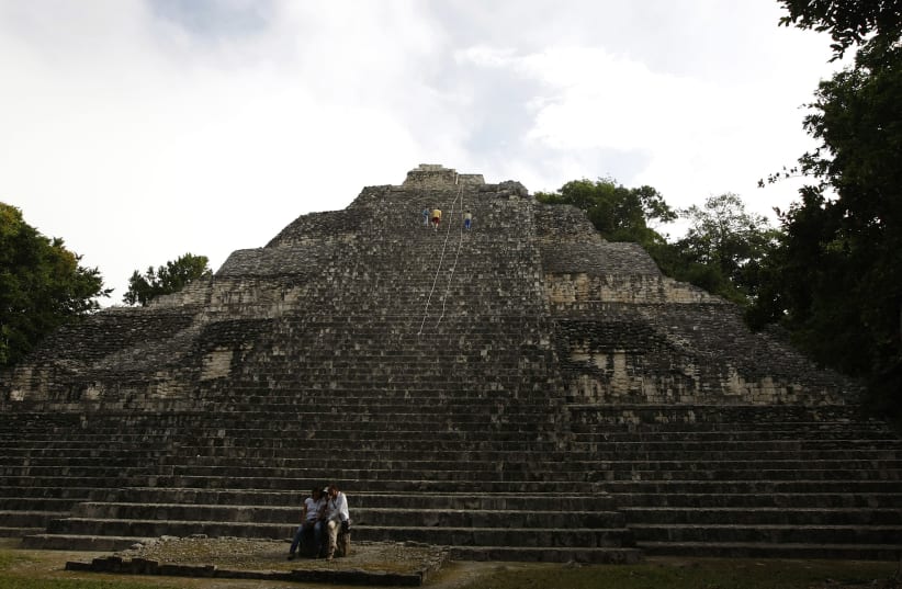 People sit at the base of a pyramid in the archaeological site of Becan at the Calakmul Biosphere Reserve in Campeche (photo credit: REUTERS)