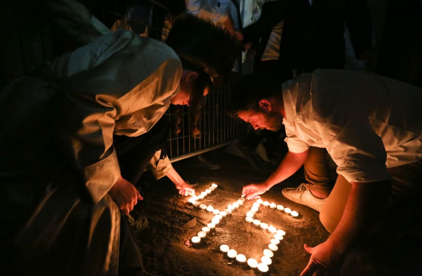 Ultra-orthodox Jews light candles for the 45 victims who were killed in a stampede, at the scene of the fatal disaster, at Mt Meron. May 01, 2021. (photo credit: DAVID COHEN/FLASH 90)