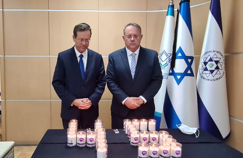 Jewish Agency Chairman Isaac Herzog (left) and Acting director of the WZO Yaakov Haguel (right) light memorial candles for the victims of the Mount Meron tragedy, Sunday, May 2, 2021. (photo credit: THE JEWISH AGENCY)