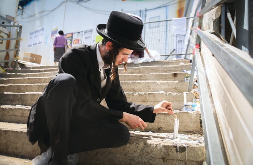 A VISITOR lights a candle at the site where 45 victims were killed in a stampede last week at Mount Meron. (photo credit: DAVID COHEN/FLASH 90)