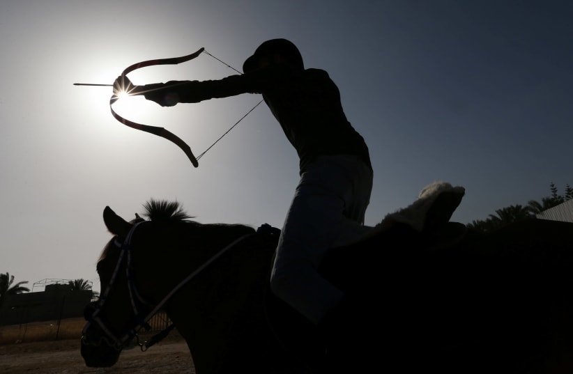 A young Palestinian rider shoots an arrow at a target during a horseback archery training session in Zawayda in the central Gaza Strip April 28, 2021. Picture taken April 28, 2021. (photo credit: IBRAHEEM ABU MUSTAFA / REUTERS)