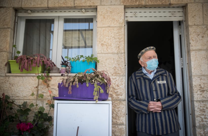 Joseph Kleinman, a 90-year-old holocaust survivor who survived Auschwitz and Dachau Nazi death camp wearing a face mask as he stands at his porch in Jerusalem, during the Holocaust Remembrance Day, April 21, 2020.  (photo credit: YONATAN SINDEL/FLASH 90)