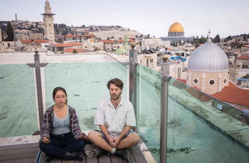 YOUNG TOURISTS meditate on the Austrian Hospice rooftop, in the Old City. (photo credit: NATI SHOHAT/FLASH90)