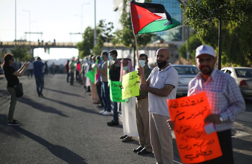 Protesters hold placards and Jordanian national flags as they take a part in a human chain during a sit-in against the annexation of parts of the West Bank by Israel, in Amman, Jordan, June 27, 2020. (photo credit: REUTERS/MUHAMMAD HAMED)