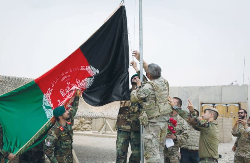 US AND AFGHANI troops attend a handover ceremony at Camp Anthonic in Helmand Province, Afghanistan, earlier this month. (photo credit: DEFENSE MINISTRY PRESS OFFICE/REUTERS)