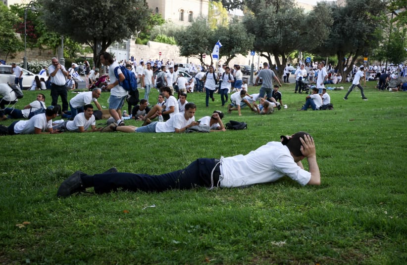 Israelis take cover as a siren sounds warning of incoming rockets from the Gaza Strip, during Jerusalem day, in Jerusalem, May 10, 2021.  (photo credit: FLASH90)