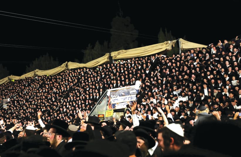 Jewish worshippers sing and dance as they stand on tribunes at the Lag Ba’omer event on Mount Meron on April 29. (photo credit: STRINGER/ REUTERS)