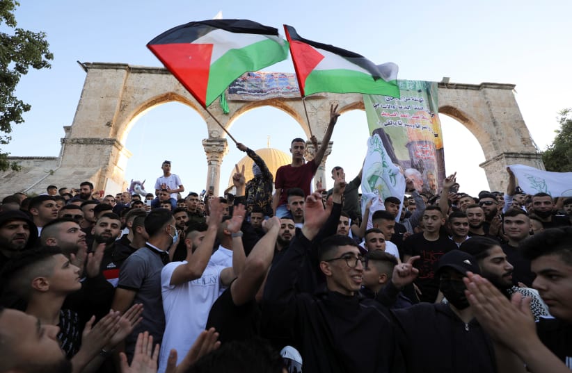 People wave Palestinian flags during Eid al-Fitr prayers, which marks the end of the holy fasting month of Ramadan, at the compound that houses al-Aqsa mosque, known to Muslims as Noble Sanctuary and to Jews as Temple Mount, in Jerusalem's Old City (photo credit: AMMAR AWAD/REUTERS)