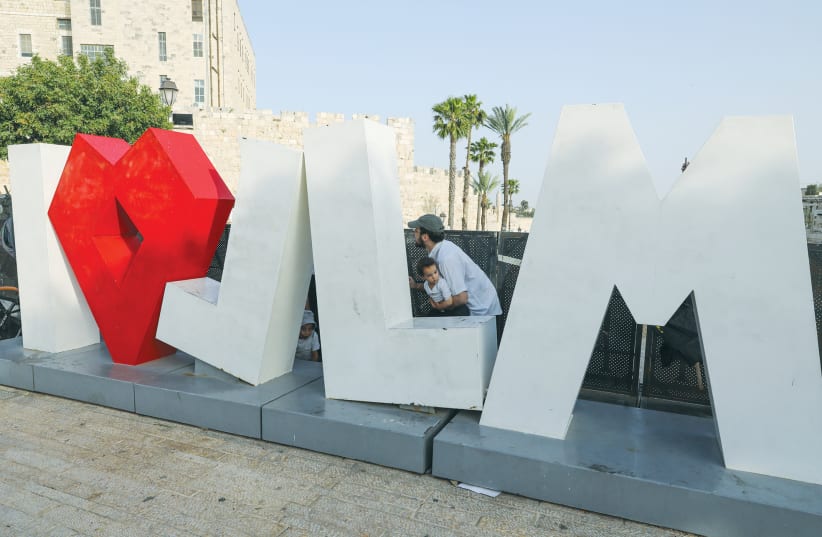 A FAMILY SHELTERS behind the ‘I love Jerusalem’ sign as Hamas fired rockets on the capital on May 10. (photo credit: MARC ISRAEL SELLEM/THE JERUSALEM POST)