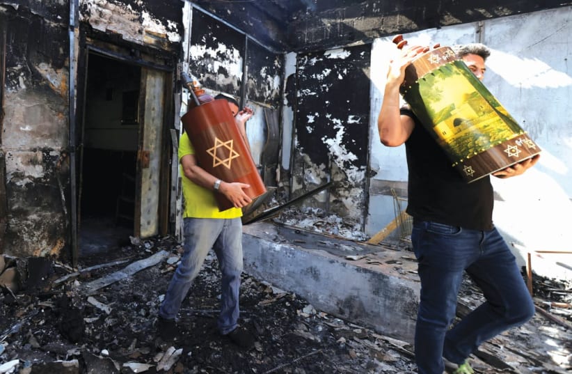 TORAH SCROLLS are removed on Wednesday from a synagogue in Lod which was torched by Arab residents the night before. (photo credit: RONEN ZVULUN/REUTERS)