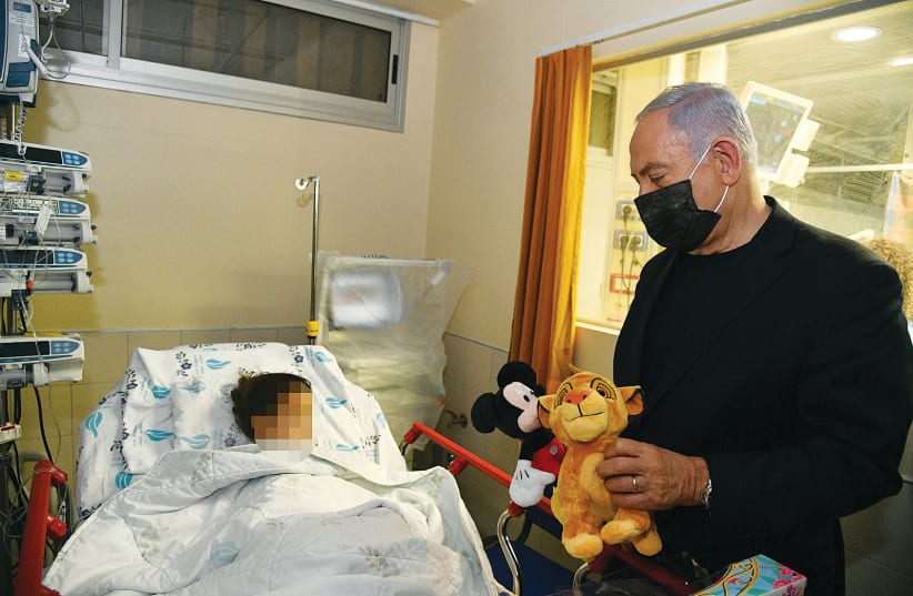 PRIME MINISTER Benjamin Netanyahu brings a toy to an injured child at Wolfson Medical Center (photo credit: HAIM ZACH/GPO)