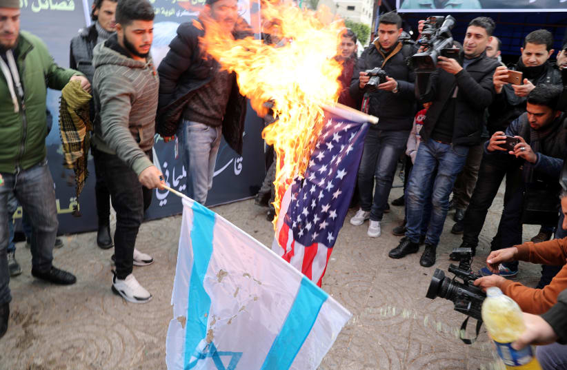 Palestinians burn representations of a U.S. flag and an Israeli flag during a protest (photo credit: MOHAMMED SALEM/REUTERS)