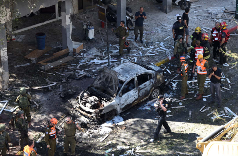 Police and rescue personnel at the scene of a rocket hit in Ramat Gan which was fired from the Gaza stripl, leaving one Israeli dead on May 15, 2021. (photo credit: GILI YAARI/FLASH90)