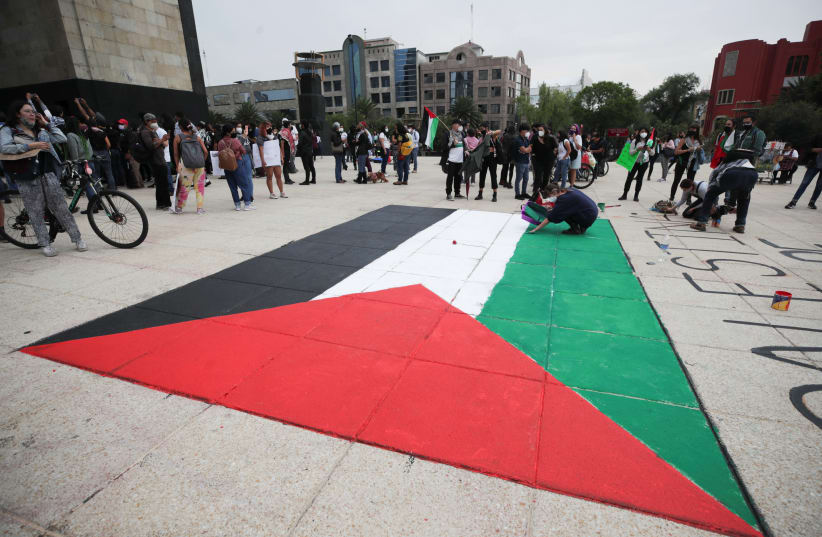 People stand near a Palestinian flag painted on the ground at the Monument to the Revolution during a pro-Palestine demonstration, amid the escalating flare-up of Israeli-Palestinian violence, in Mexico City, Mexico May 15, 2021. (photo credit: HENRY ROMERO / REUTERS)