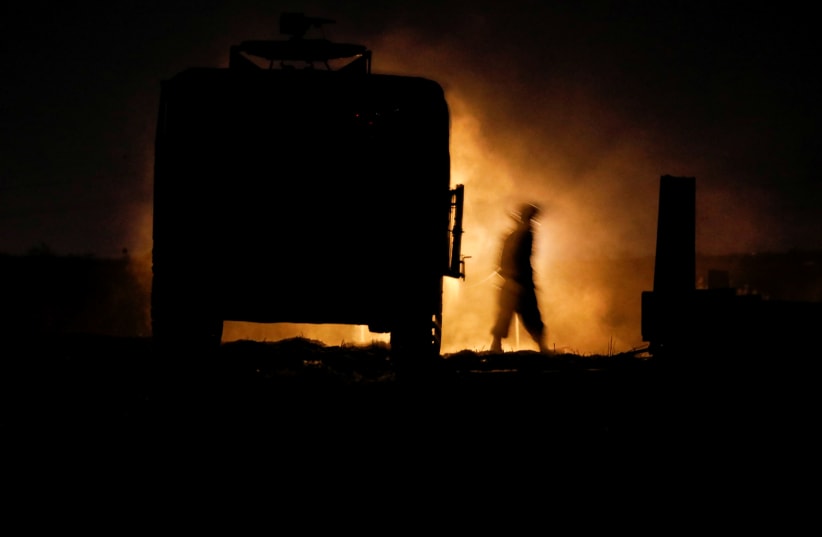 An Israeli soldier walks next to a military vehicle at a mobile artillery unit location on the Israeli side by the Israel border with Gaza (photo credit: BAZ RATNER/REUTERS)