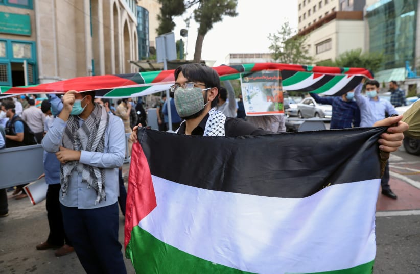 An Iranian man holds a Palestinian flag during a protest to express solidarity with the Palestinian people amid a flare-up of Israeli-Palestinian violence, in Tehran, Iran May 18, 2021. (photo credit: MAJID ASGARIPOUR/WANA (WEST ASIA NEWS AGENCY) VIA REUTERS)