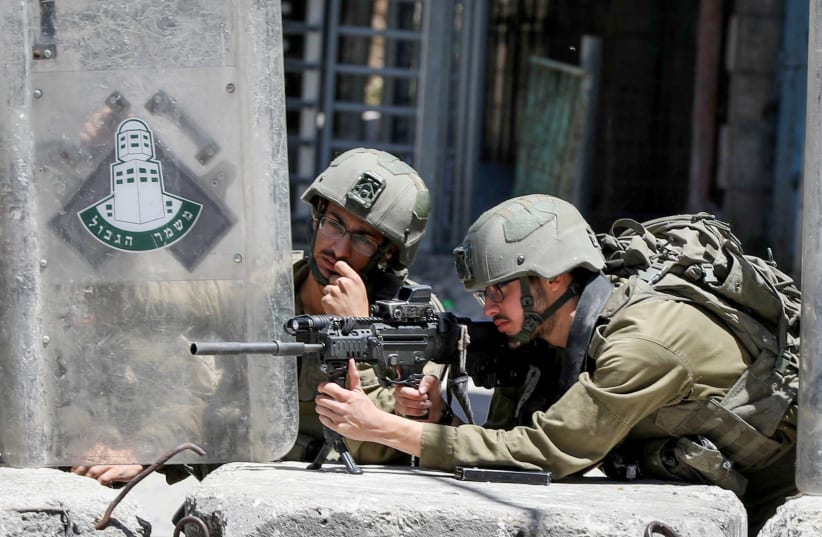 IDF forces and Palestinian youth clash in Hebron, May 18, 2021 (photo credit: WISAM HASHLAMOUN/FLASH90)