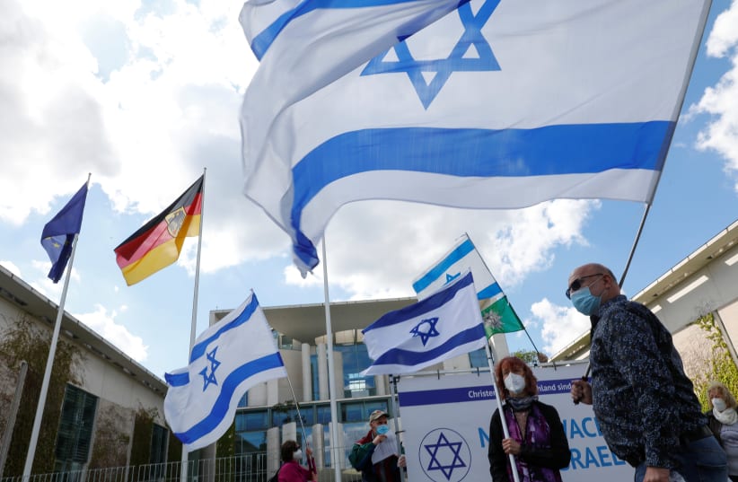 People wave the flags of Israel and the Trade Union of the Police outside the Chancellery in Berlin, Germany, May 19, 2021. (photo credit: MICHELE TANTUSSI/REUTERS)