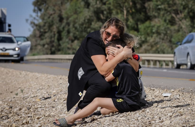 A woman and child take cover as a siren sounds a warning of incoming rockets fired from the Gaza strip in the city of Ashkelon, southern Israel, on May 19, 2021.  (photo credit: OLIVIER FITOUSSI/FLASH90)