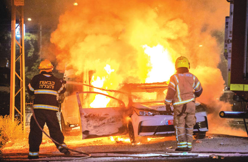 FIREFIGHTERS EXTINGUISH a police car in Lod that was torched along with shops and other property by Arab residents rioting in the city last Wednesday. (photo credit: YOSSI ALONI/FLASH90)