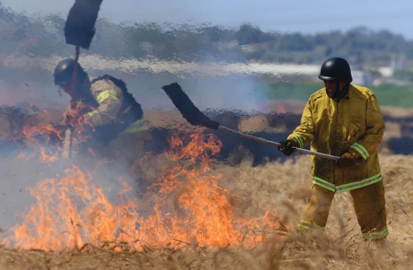 EXTINGUISHING FLAMES caused by a rocket fired from Gaza, May 16 (photo credit: TOMER NEUBERG/FLASH90)