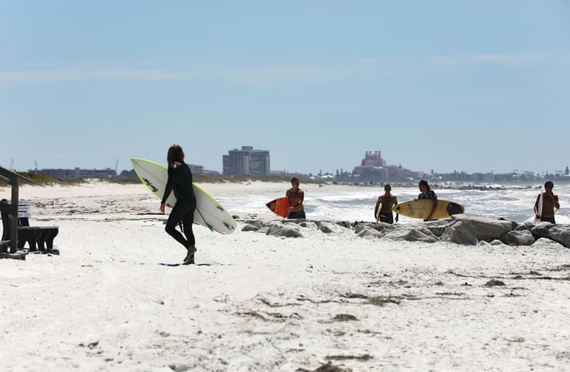 SURFERS RIDE waves in Treasure Island, Florida last year – the setting for the murder mystery novel (photo credit: EVE EDELHEIT/REUTERS)