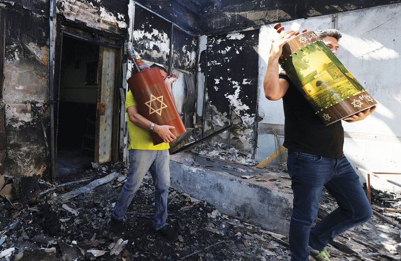 Torah scrolls are removed last week from a synagogue in Lod that had been torched by Arab residents the night before. (photo credit: RONEN ZVULUN/REUTERS)