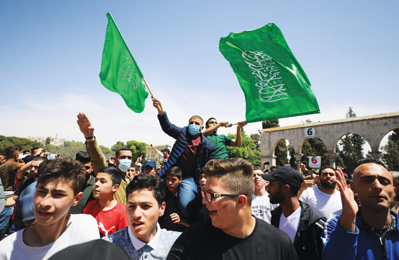 PALESTINIANS WAVE Hamas flags on the last Friday of Ramadan in protest over the possible eviction of families in Jerusalem’s Sheikh Jarrah neighborhood, earlier this month. (photo credit: AMMAR AWAD/REUTERS)