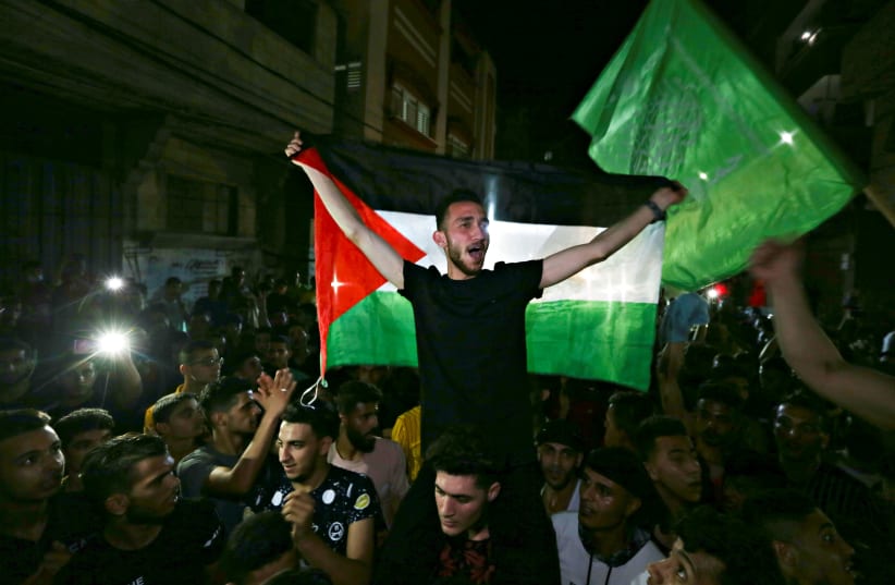 Palestinians celebrate in the streets following a ceasefire, in the southern Gaza Strip May 21, 2021. (photo credit: IBRAHEEM ABU MUSTAFA/REUTERS)