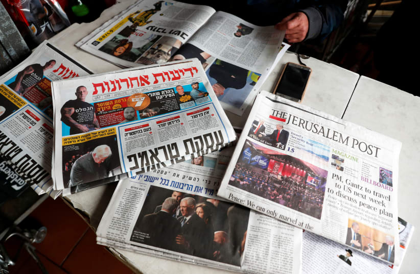 A man sits in a coffee shop next to the main Israeli Newspapers in Jerusalem (photo credit: RONEN ZVULUN/REUTERS)