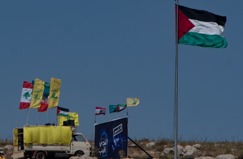 Palestinian and Lebanese flags are seen waving at a protest on the Lebanese-Israeli border in support of the Palestinian people, on May 20, 2021. (photo credit: BASEL AWIDAT/FLASH90)