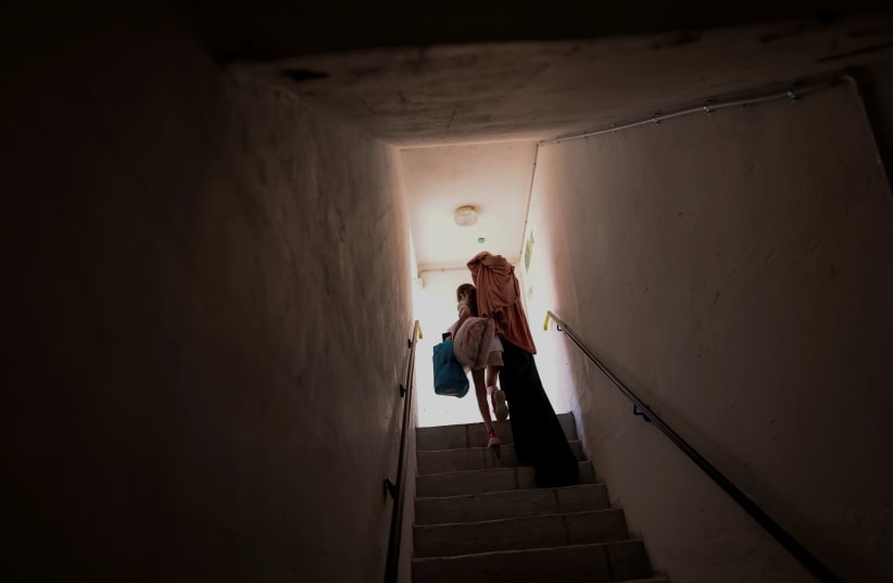An Israeli girl carries her belongings as she walks out from a public bomb shelter back home, following Israel-Hamas truce, in Ashkelon, Israel May 21, 2021. (photo credit: RONEN ZVULUN/REUTERS)