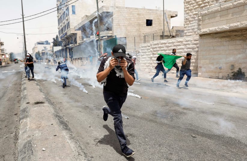 Photojournalists and Palestinian demonstrators run away from tear gas fired by Israeli forces during an anti-Israel protest, in Bethlehem in the West Bank May 21, 2021. (photo credit: MUSSA QAWASMA/REUTERS)