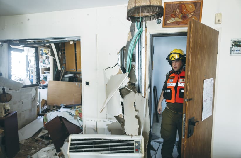 A SECURITY OFFICIAL checks an apartment in Ashdod following a rocket attack from Gaza on Monday. (photo credit: RONEN ZVULUN / REUTERS)