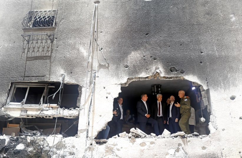 Israeli Foreign Minister Gabi Ashkenazi speaks to his Czech counterpart Jakub Kulhanek and Slovak counterpart Ivan Korcok as they visit the site of a building damaged by a rocket launched from the Gaza Strip last week, in Petah Tikva, Israel May 20, 2021. (photo credit: NIR ELIAS / REUTERS)