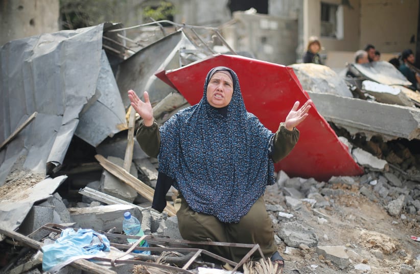 A WOMAN reacts after returning to her destroyed house in the Gaza Strip following the start of the Israel-Hamas truce, on Friday. (photo credit: IBRAHEEM ABU MUSTAFA / REUTERS)