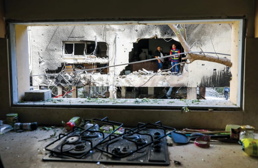 Residents inspect damage to their home in Petah Tikva by a rocket fired from Gaza, May 13, 2021 (photo credit: MARC ISRAEL SELLEM/THE JERUSALEM POST)