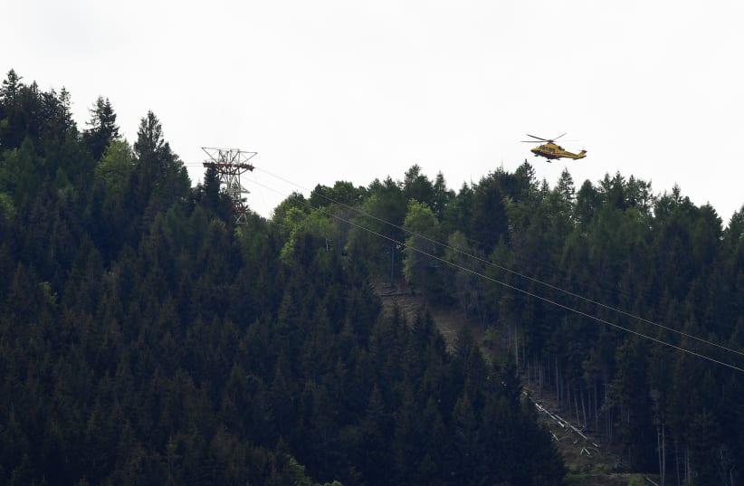 A helicopter flies over the site where a cable car connecting Maggiore lake with a mountain close by collapsed, in Stresa, Italy, May 23, 2021. (photo credit: REUTERS/FLAVIO LO SCALZO)